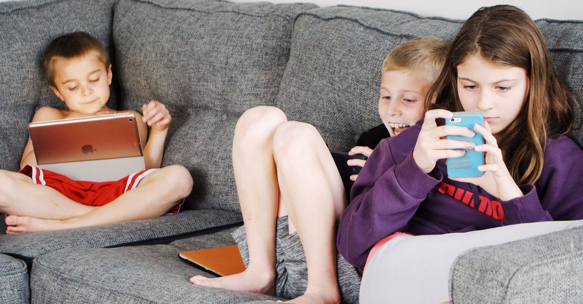 How do I use game tickets? - Positive barefoot children in casual wear resting together on cozy couch and browsing tablets and smartphones