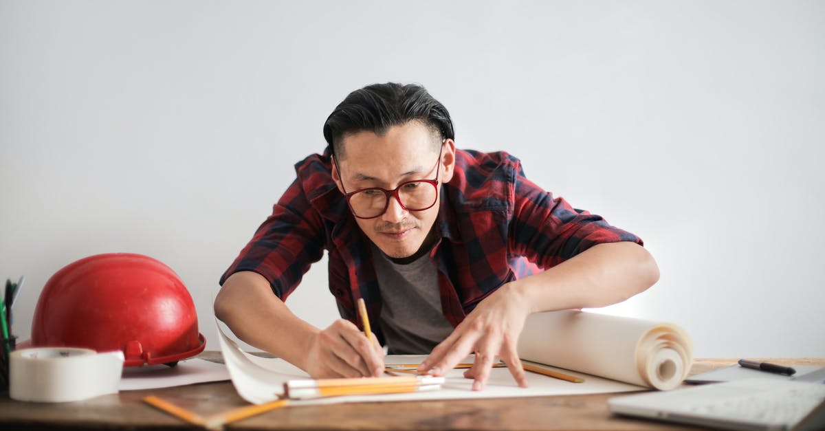 How do Measure weapons work? - Inspired young male engineer in glasses drawing draft on paper bending over table against white wall