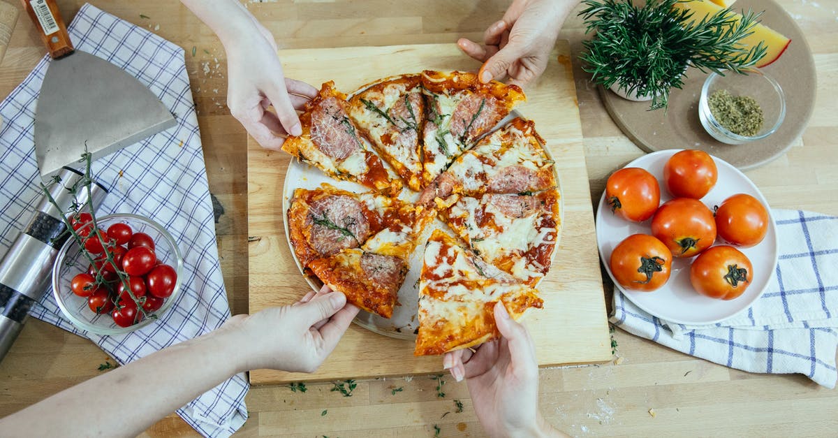 How do you divide the Muzzarella pizza into 7 parts? - From above unrecognizable people taking slices of pizza with salami melted cheese and herbs from plate on kitchen table