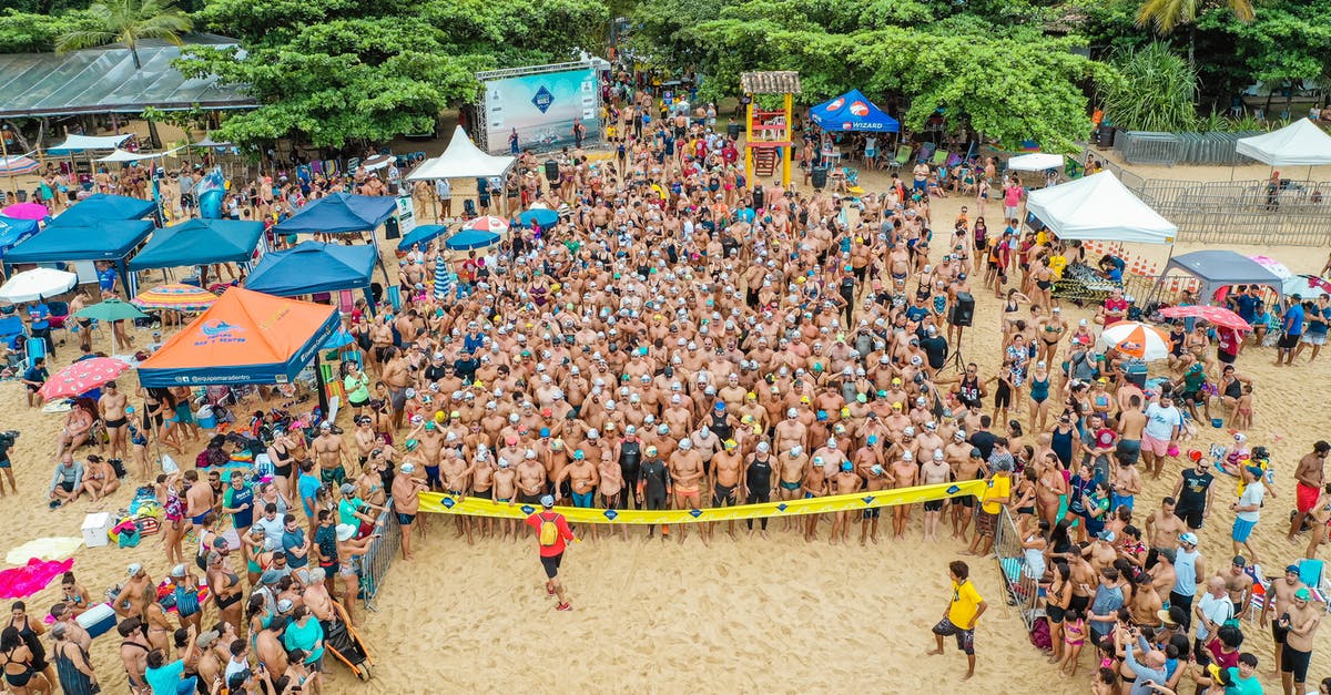 How do you do the jump start in Beach Buggy Racing? - Drone view of crowd of people in swimsuits standing behind line tape on sandy beach beginning race