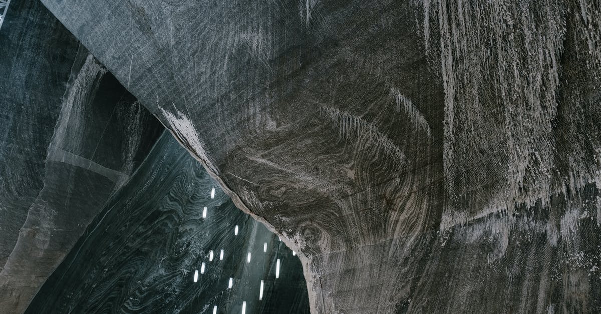 How do you get miners to mine for gems? - Low angle of abstract textured walls and hanging LED lamps in Salina Turda salt mine in Romania