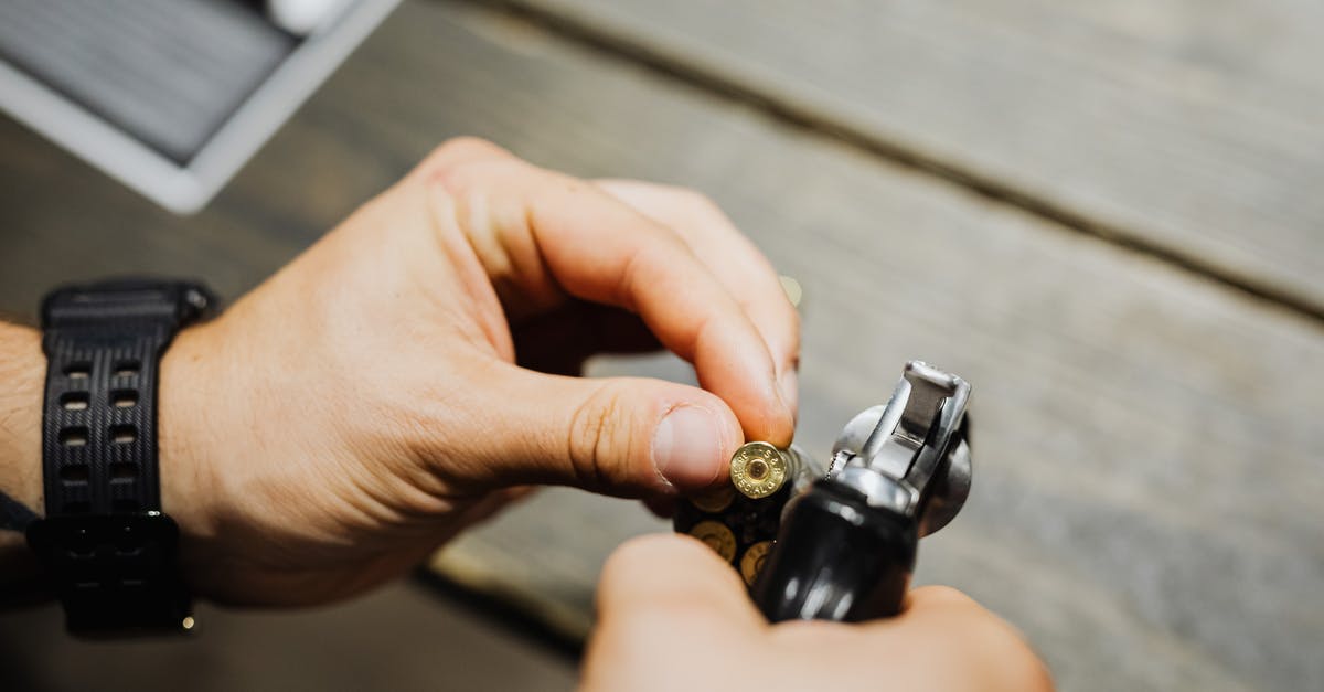 How does 2-handing a weapon affect damage? - Hands of a Person Holding a Gold Bullet and a Pistol