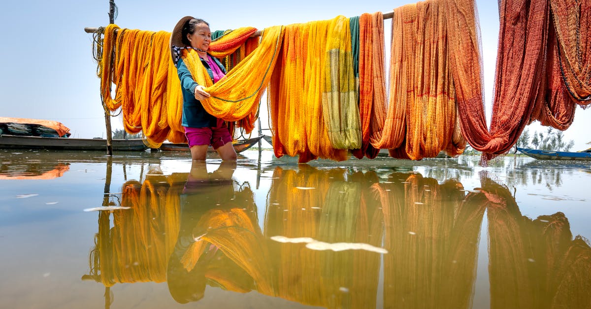 How does a losing battalion choose what province to return to? - Positive middle aged Asian female in casual clothes standing in river water and choosing colorful fishing net hanging on bamboo pole on sunny day in Thua Thien Hue Province How does a losing battalion choose what province to return to? - Positive middle aged Asian female in casual clothes standing in river water and choosing colorful fishing net hanging on bamboo pole on sunny day in Thua Thien Hue Province