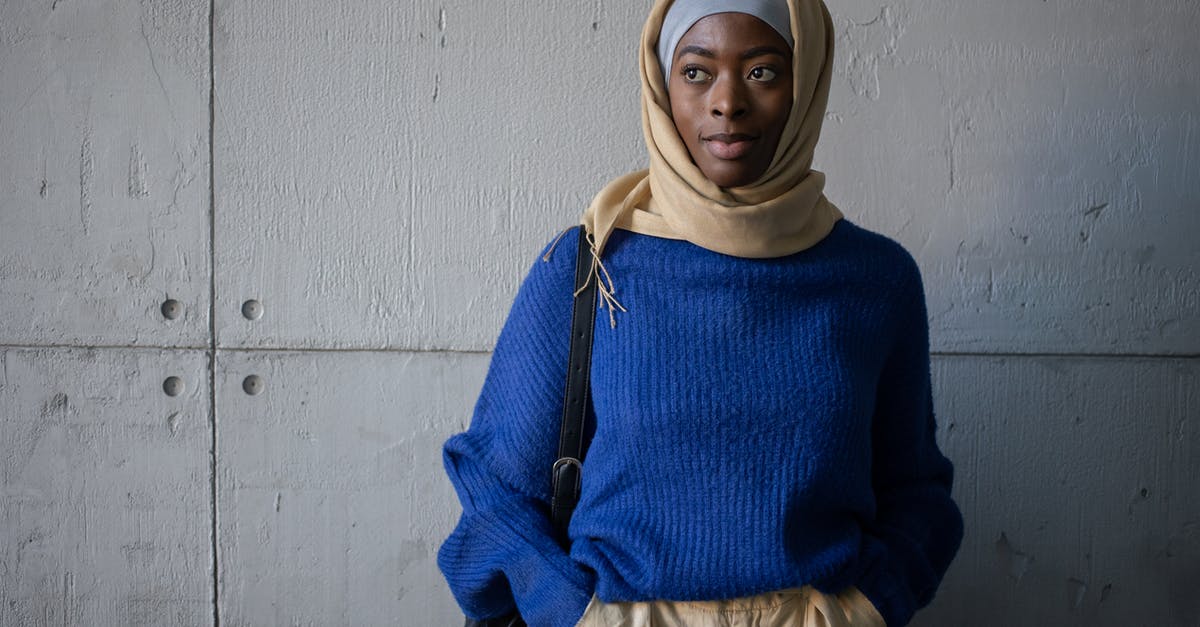 How does one conquer Native Americans and not loose diplomatic points? - Content Muslim female student in traditional headscarf wearing blue sweater looking away while standing near wall with backpack in corridor of university