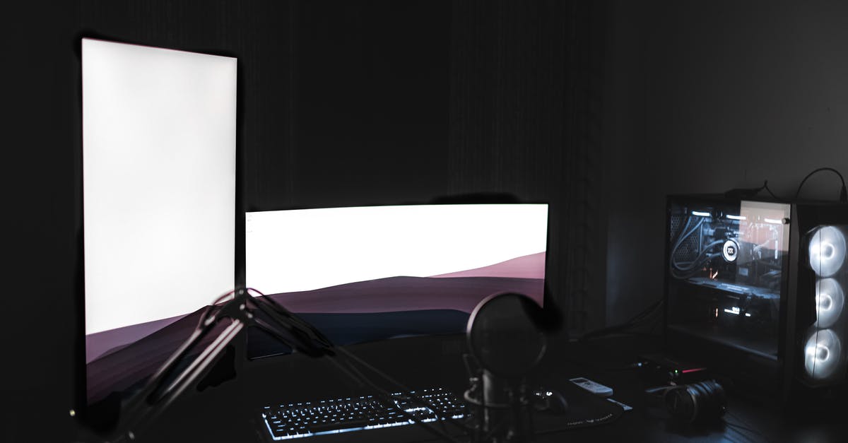 How does the Amazon Prime Gaming rewards system work? - Gaming setup with glowing modern monitors placed on black table with keyboard near microphone and system unit in dark room