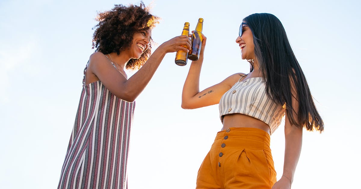 How does the passive item Unity add damage from your other guns? - Low angle of delighted multiracial female friends toasting with bottles of beer while laughing together during party