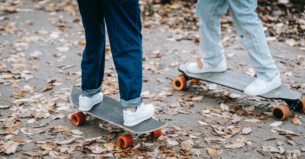 How fast do skills degrade? - Crop legs of anonymous people in jeans and sneakers riding skateboards on asphalt walkway in park in autumn day