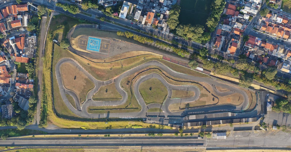 How good is auto-drift in Mario Kart 8? - Top view of asphalt racetrack for kart riding located in green town surrounded by trees in sunny day