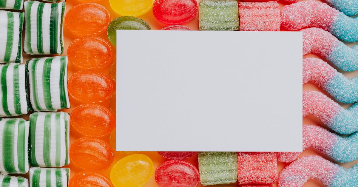 How likely is it to pull a character from data cards? - Top view closeup of blank paper card placed on multicolored various shapes yummy candies in light confectionery