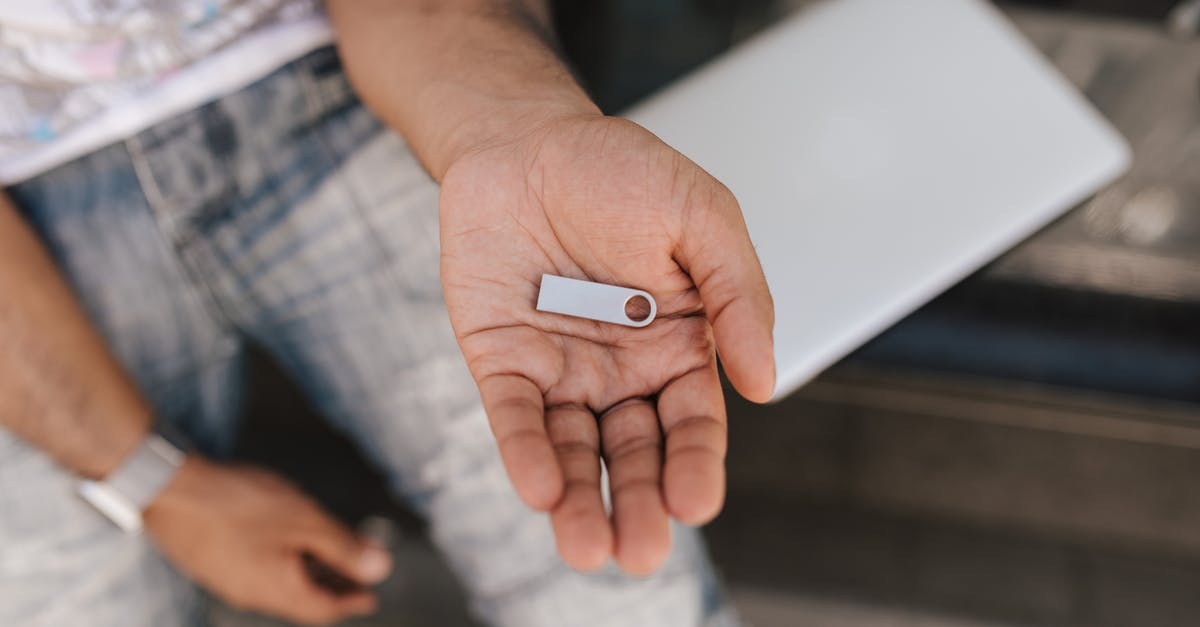 How likely is it to pull a character from data cards? - From above crop male in casual outfit sitting on street bench with laptop and demonstrating flashcard on hand