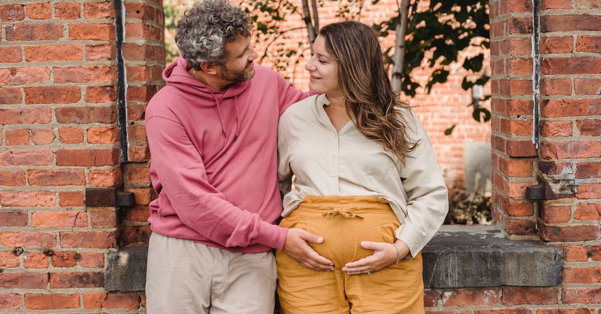 How long can we expect an Atari 2600 cartridge to last? - Delighted adult male with curly gray hair standing with smiling pregnant female near brick wall and touching tummy