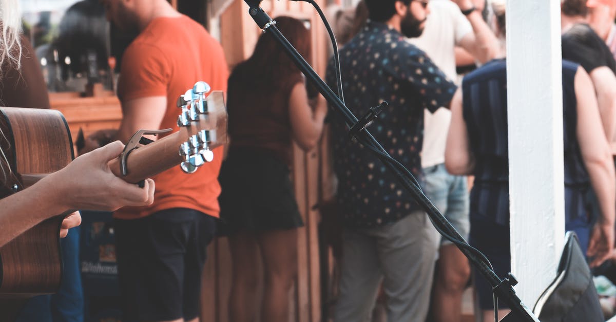 How many players are required to play the Jackbox party games? - Crop anonymous person with acoustic guitar at festival with many people in daytime