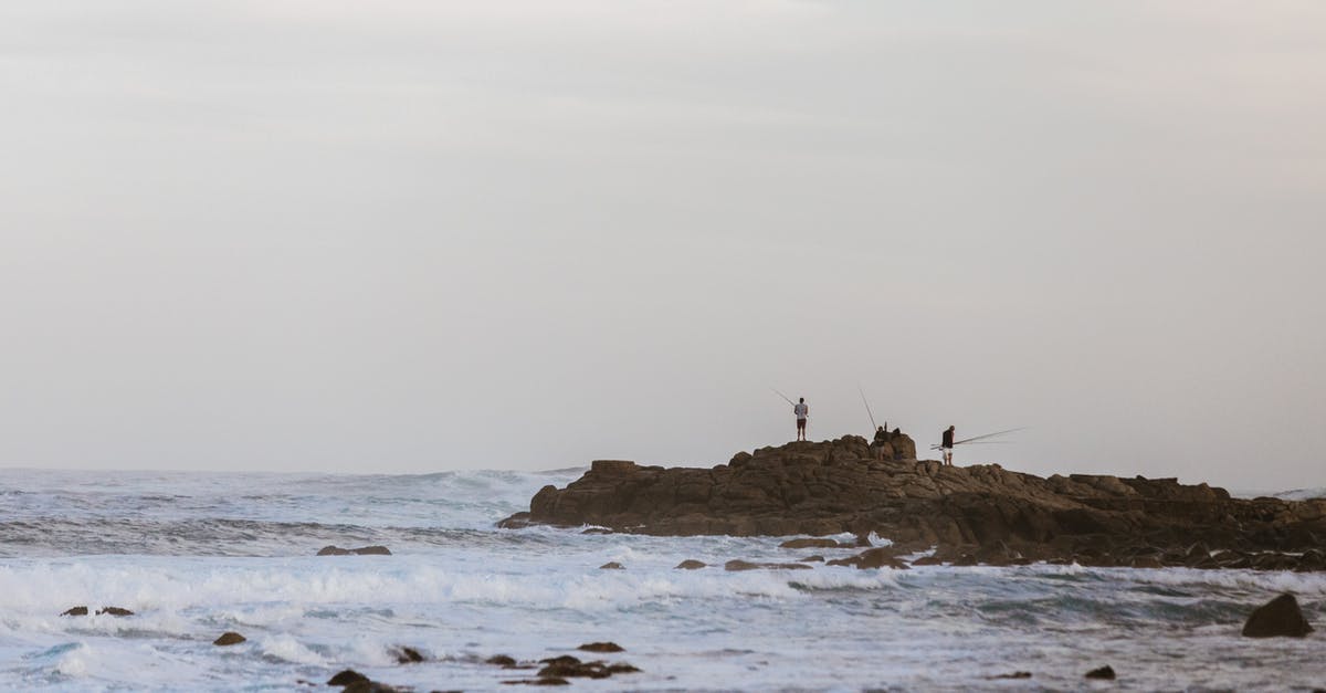 How to catch Pokemon... with a rod? - Faceless fishermen on rock catching fish in sea