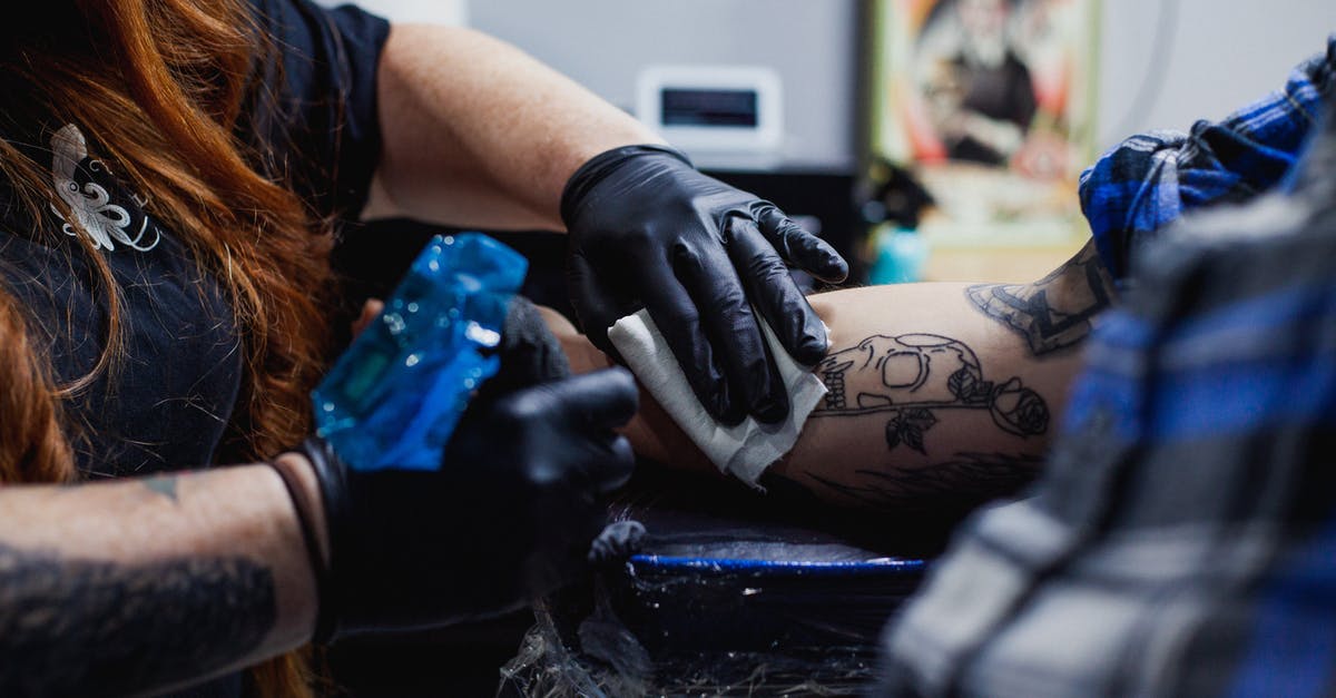 How to create a Custom GUI? - Faceless woman in black gloves doing tattoo with gun on arm of man in salon