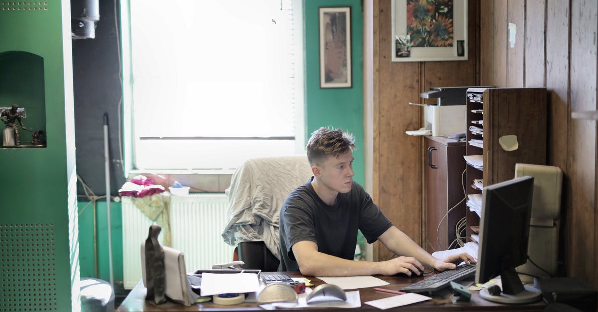 How to develop a buying strategy? - Concentrated male in casual clothes sitting at table and using desktop while working in office