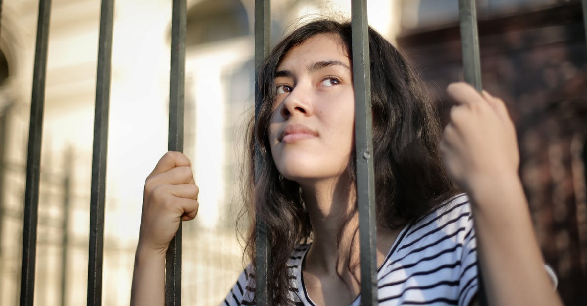 How to escape when cornered by enemies? - Sad isolated young woman looking away through fence with hope