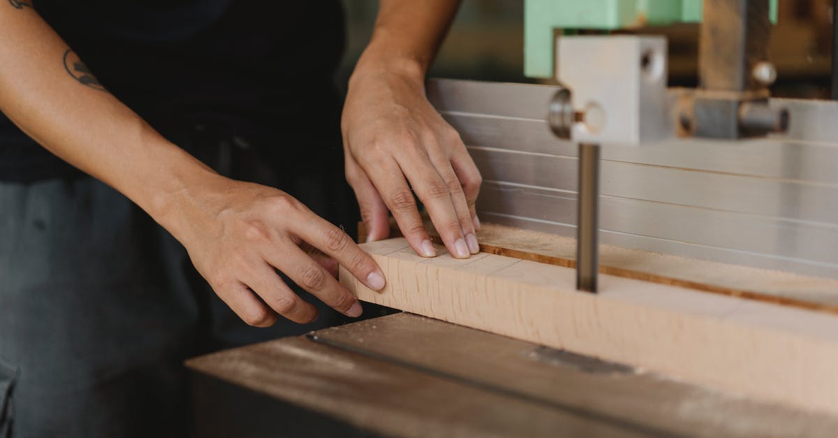 How to fill a block with an Armor Stand - Crop anonymous male joiner sawing wooden block with electric machine on table in workroom