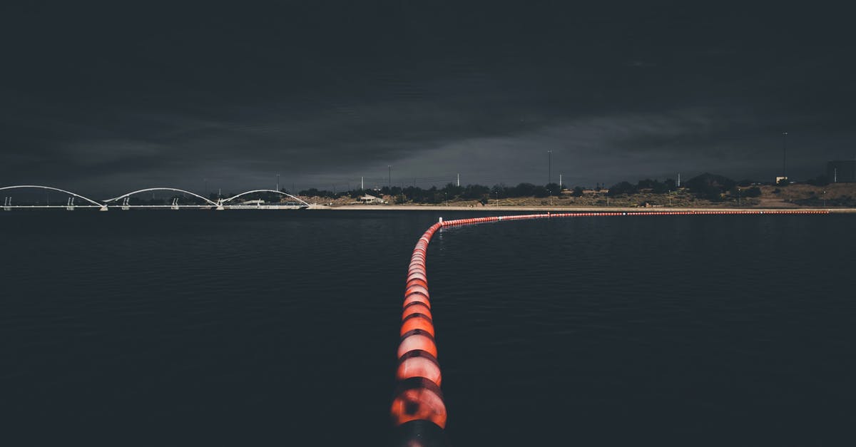 How to find and use Dark Zone keys? - From above of illuminated buoy line floating in dark water of lake near modern bridge against night sky