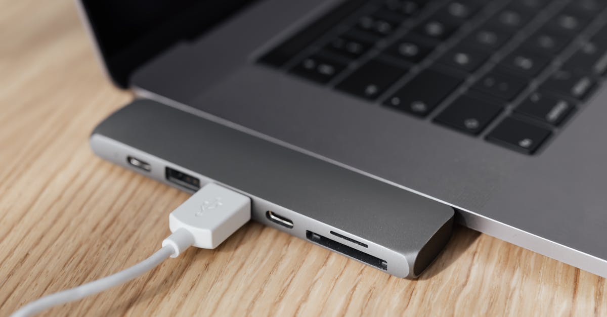 How to fix a dead usb port on PS4? - High angle of modern space silver laptop with USB type c multiport hub with plugged white cable placed on wooden table