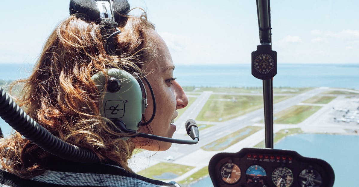 How to get female crew I failed to claim - Back view of positive young female traveler in casual wear and headset sitting in cockpit of modern helicopter during flight over coastal town