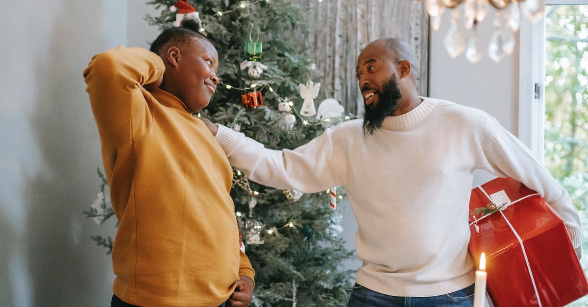 How to give relative rotation to armor stand? - Happy bearded African American man with red box touching shoulder of cheerful black son with hand behind head during Christmas holiday while looking at each other