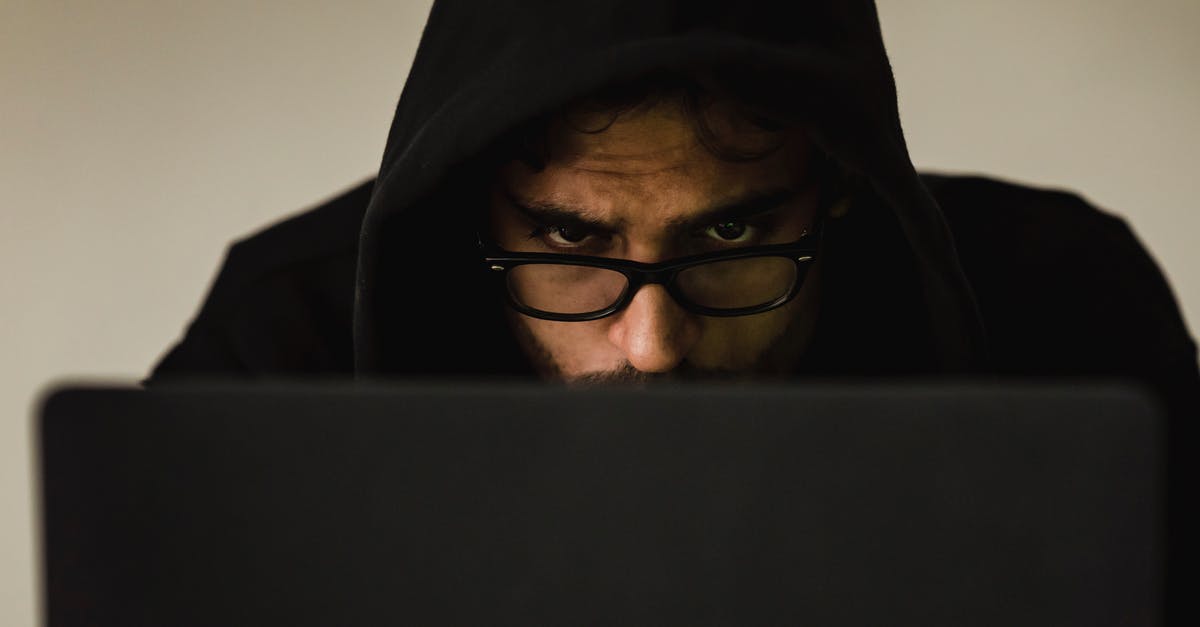 How to hack terminals - Serious young male programmer wearing black hoodie browsing netbook and hacking software in studio