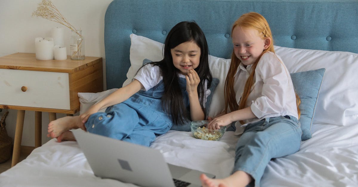 How to I unlock the Comedy Specs? - Full body of happy barefooted diverse children with long hairs lying on comfortable bed and eating popcorn while watching funny cartoon on laptop in cozy room