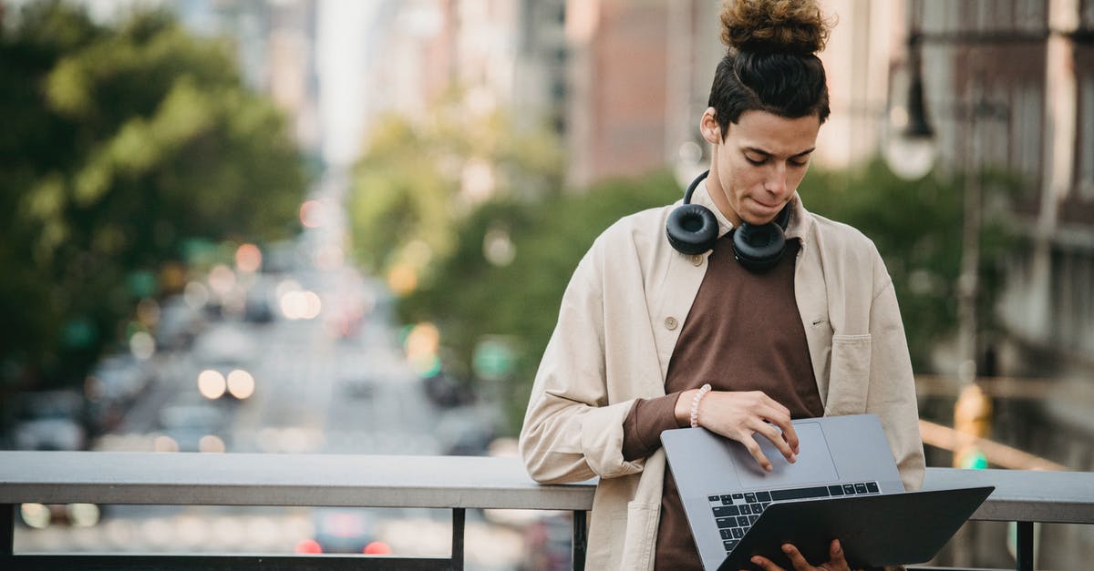 How to install the R4 software for a DSi? - Pensive ethnic young male with trendy hairstyle downloading netbook while using touchpad on bridge on blurred background of road