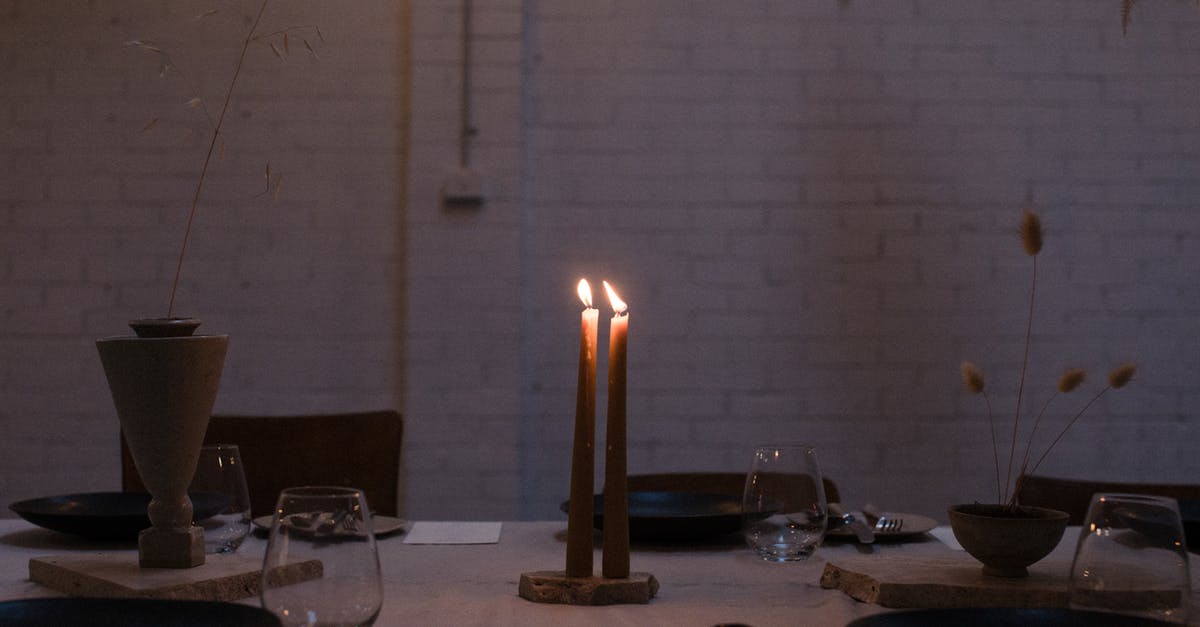 How to know if 'Unguarded Nomadic Frontier' event already fired? - Long thin flaming candles surrounded by flowers in vase and small transparent glasses on table next to brick wall in dark room