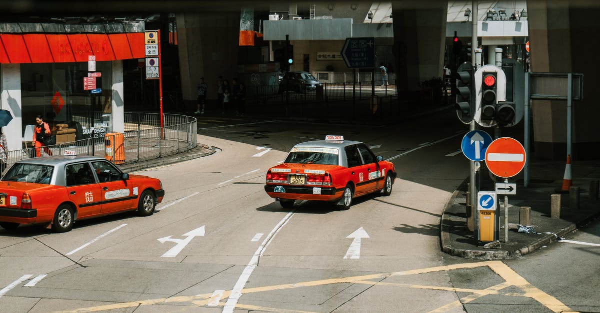 How to make a turning lane without an intersection? - From above of red taxi cars driving on asphalt street near crossroad in modern city district on sunny day