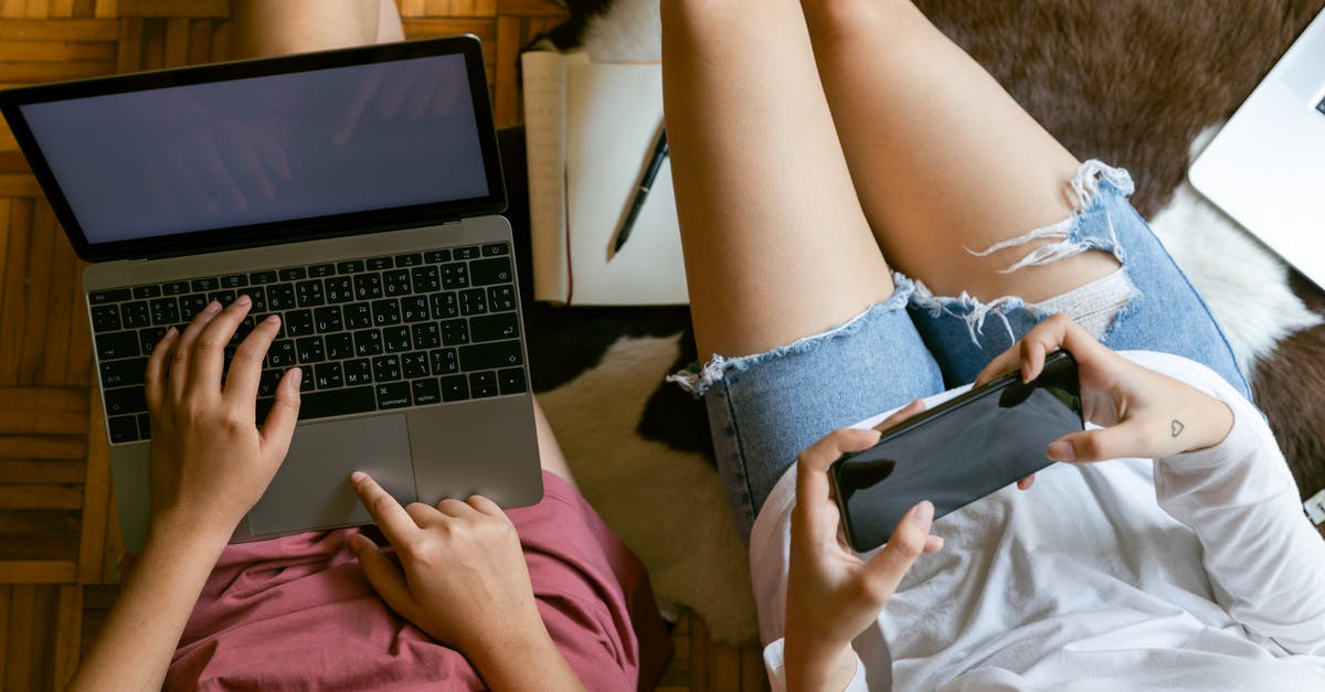 How to make FFXIV chat sticky from typing? - From above of crop girlfriends in home clothes sitting on floor with laptop and smartphone while spending time together and planning weekend