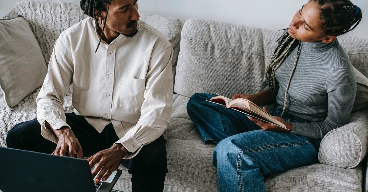 How to make FFXIV chat sticky from typing? - From above of serious young African American husband and wife in casual outfits sitting on sofa with book and laptop and discussing relationships in cozy living room