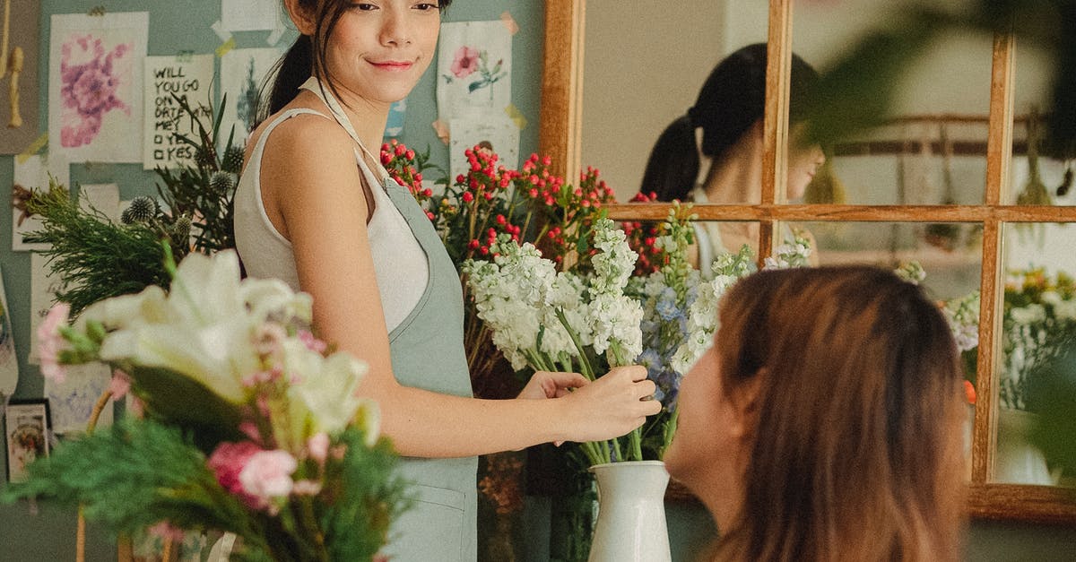 How to make mobs not attack each other? - Side view glad young female florists wearing aprons arranging delicate flowers and looking at each other contentedly while working together in light floral store