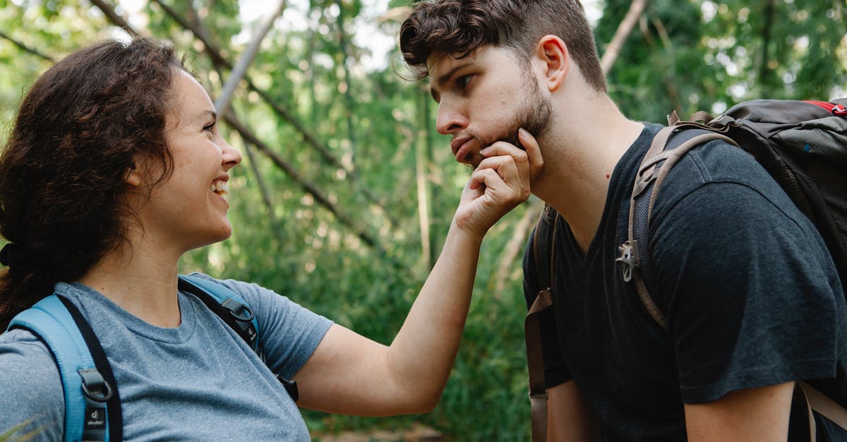 How to make mobs not attack each other? - Side view of happy young woman smiling and touching face of tired boyfriend making grimace while standing together in green forest during hiking trip