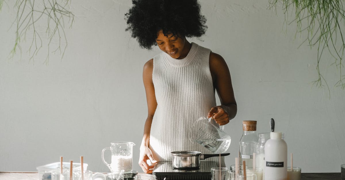 How to make voices louder in Black Mesa? - Positive African American female artisan pouring liquid in pot while making wax for candles in pot on cooker