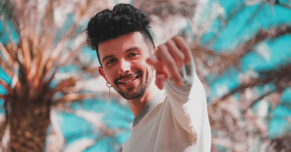 How to pick the HQ you want in skirmish mode? - Low angle of modern trendy man with earring pointing with finger at camera standing under palm trees in sunshine