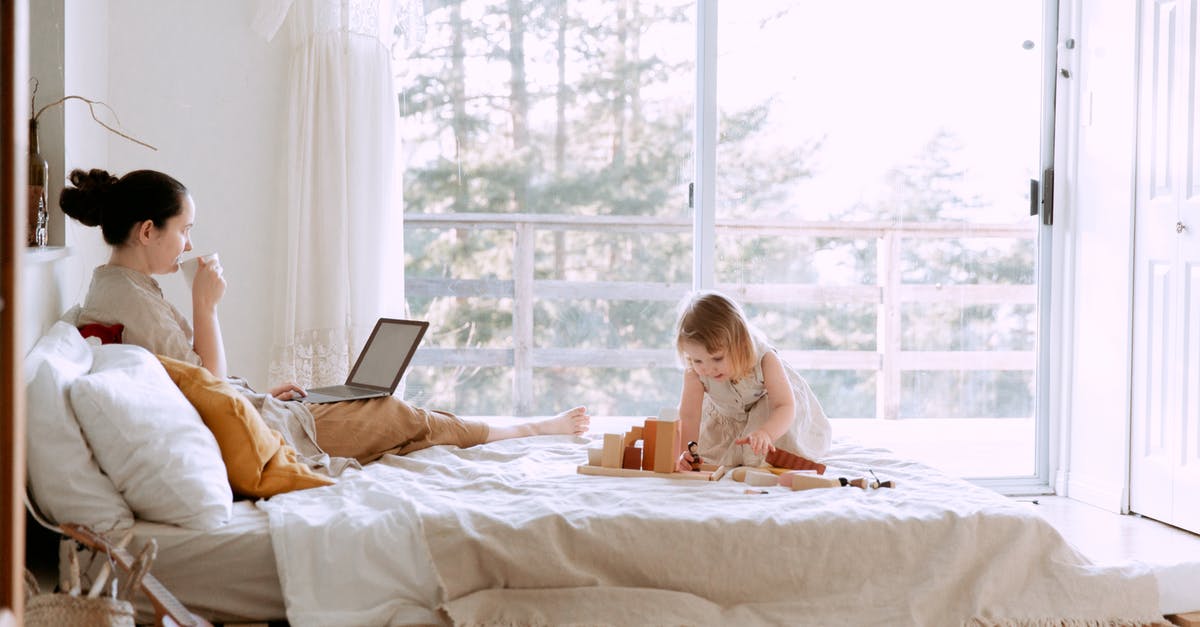 How to play Project M using a backup on USB? - Concentrated female drinking coffee while working on project on laptop and daughter sitting on bed playing with constructor in bedroom