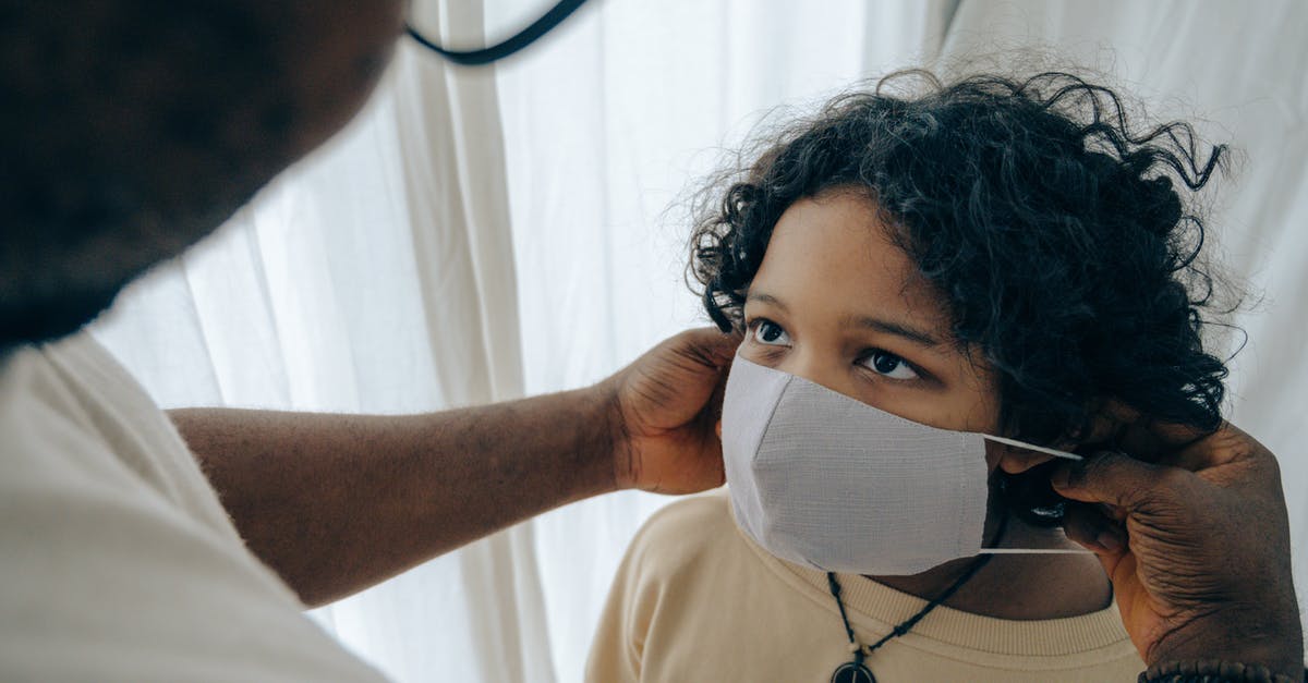 How to prevent others from changing a structure in Minecraft? - From above unrecognizable black man wearing protective mask on face of ethnic kid standing in room near window closed with curtain