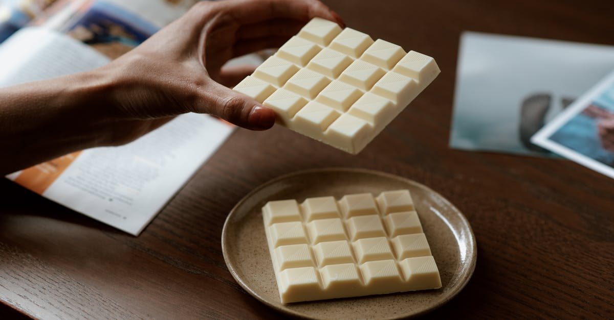 How to read a target bar - Crop faceless female holding piece of white chocolate while reading magazine and resting at home