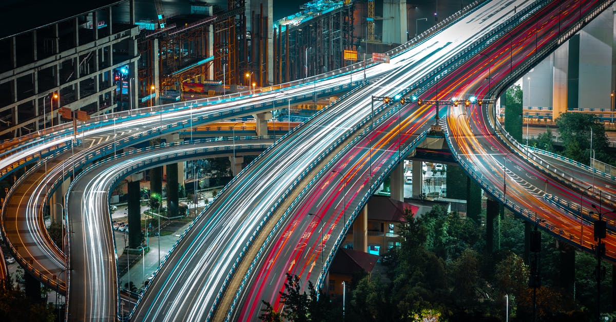 How to remove a speed boost from someone? - From above long exposure traffic on modern highway elevated above ground level surrounded by urban constructions in evening