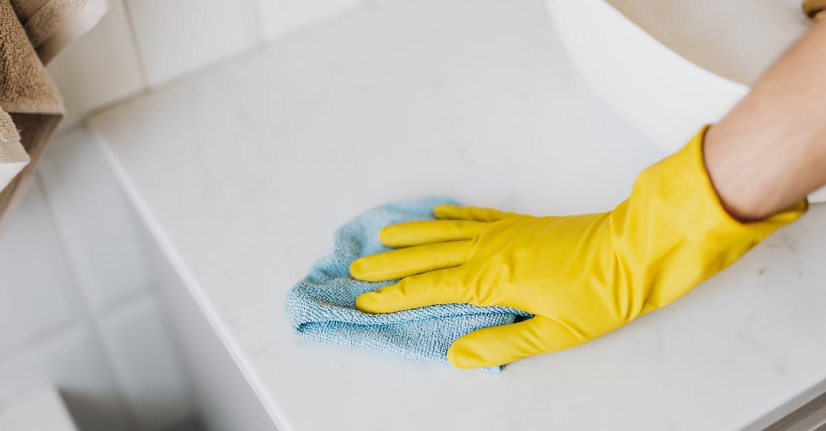 How to remove noble prisoners from dead factions? - From above crop unrecognizable person with microfiber cloth wearing yellow rubber glove and cleaning white marble tabletop of vanity table with washbasin in bathroom