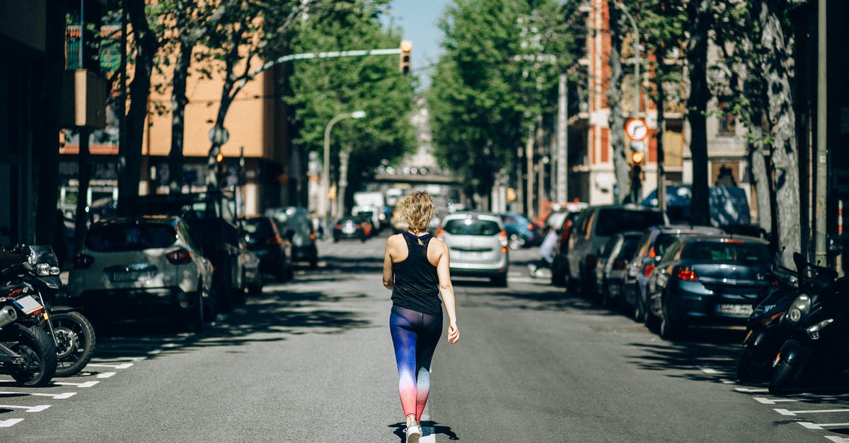 How to survive in the middle of a storm? - Woman in Black Tank Top and Blue Denim Jeans Running on Road