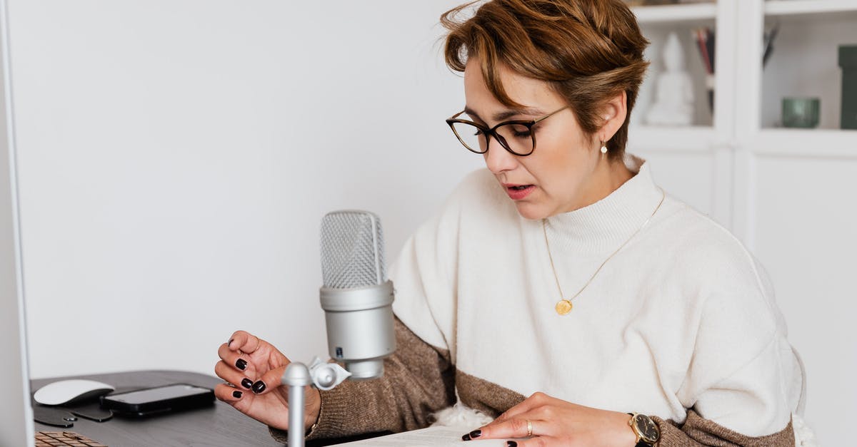 How to tell if someone is likely to attack? - Female narrator in glasses reading out loud from book while sitting at desk with microphone and recording audiobook in cozy study