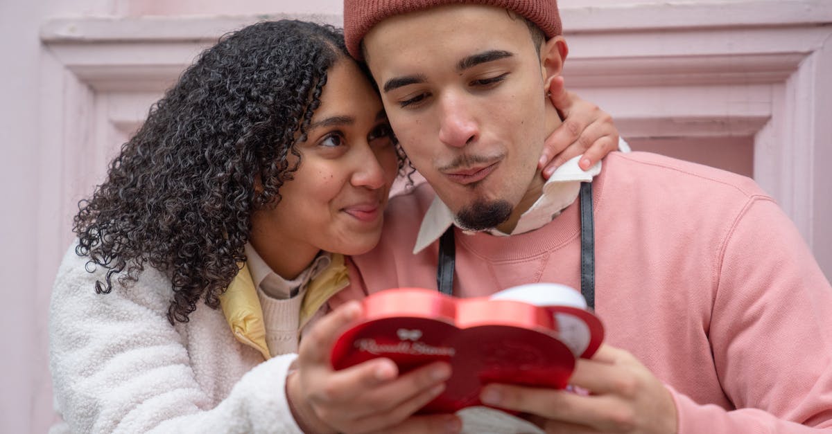 How to tranfer saves in Candy Box 2 - Joyful young ethnic couple embracing and eating yummy candies from heart shaped gift box during anniversary celebration