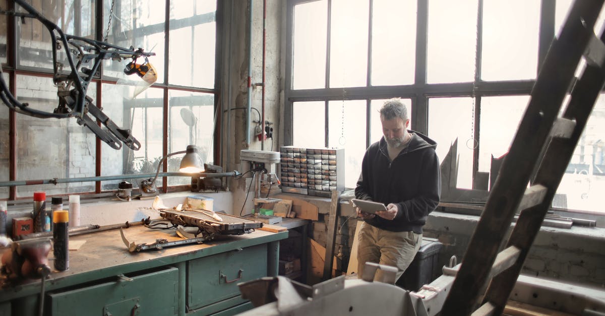 How to use TM Dig in Pokemon Emerald - Adult bearded mechanic in casual wear standing near window in workshop and browsing digital tablet