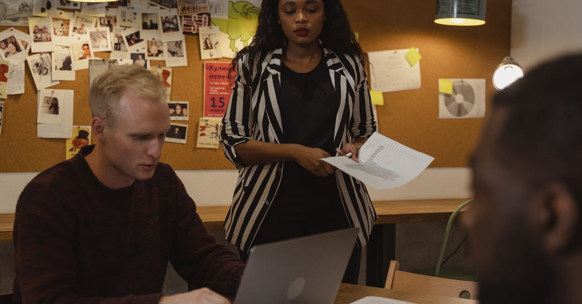 How to Use Way of White Circlet - Woman in Black and White Coat Standing Beside Man Sitting Using Laptop