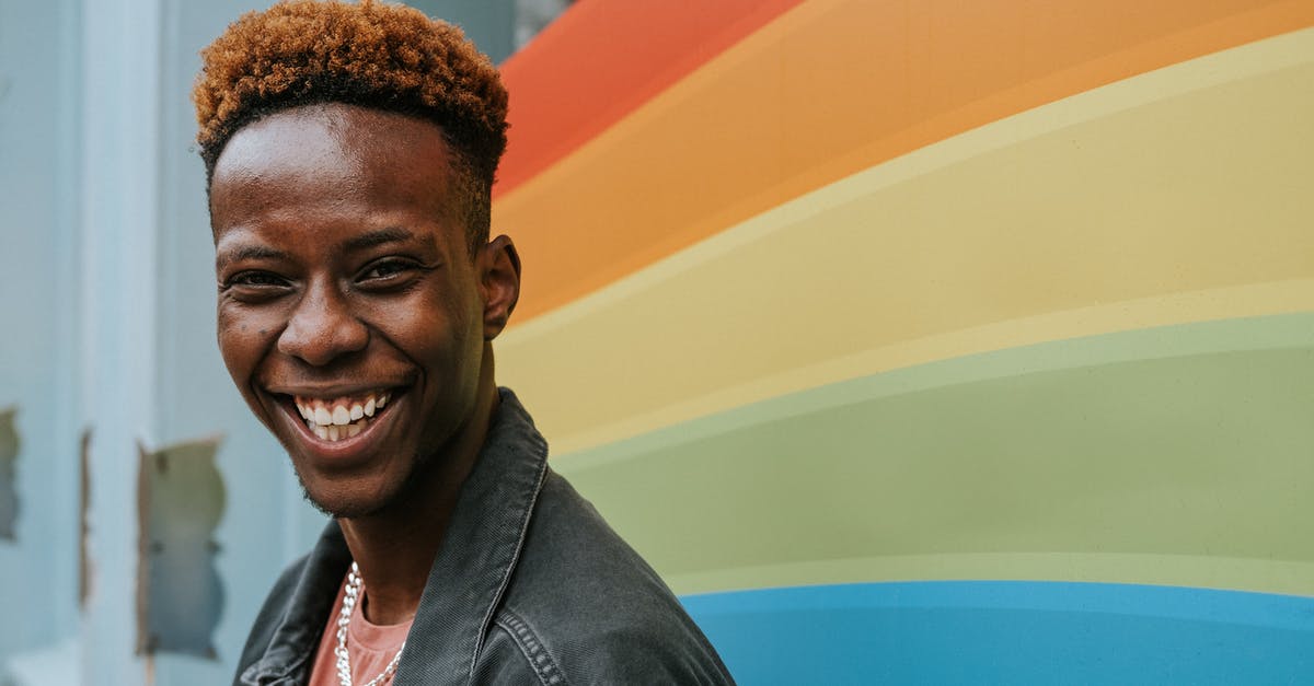 How tolerant are cuccos? - Positive young black guy laughing near graffiti wall with rainbow flag