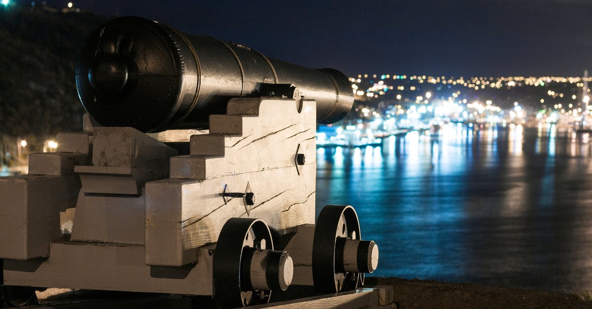 Hyper Light Drifter: How do I get past these barriers? - Vintage artillery cannon on wooden support on waterfront of city with glowing lights at night