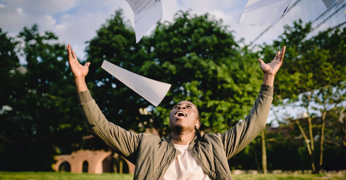 I'm stuck outside the map and I can't get out! - Cheerful young African American male student in casual clothes throwing college papers up in air while having fun in green park after end of exams