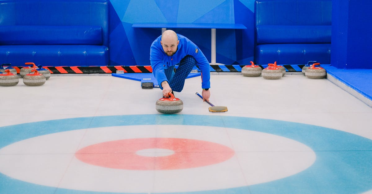 Ice Stone (Pokemon Sword) - Focused male in blue activewear choosing tactic and throwing stone while playing curling on ice rink